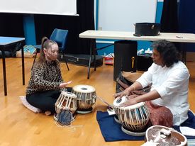 A girl and a man play tabla drums together