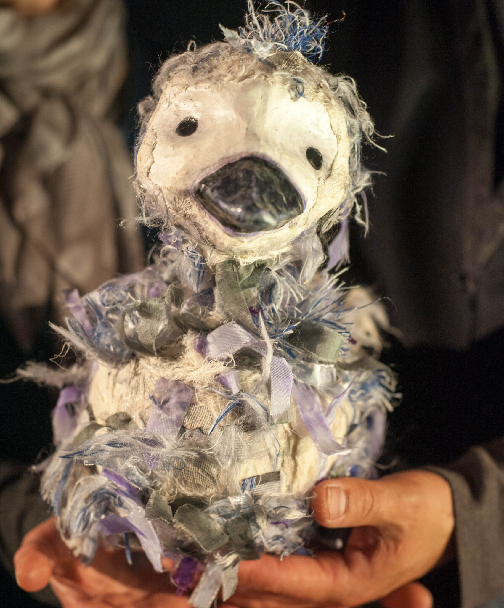 A bird puppet sits in a pair of hands