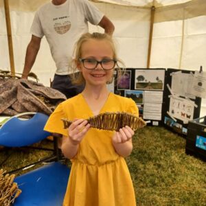 Girl smiling standing holding wooden fish in gazebo in a field