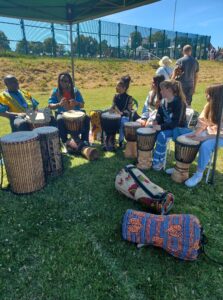Group of people sitting with drums smiling in field