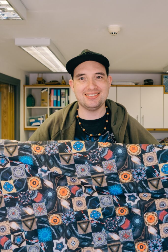 Man standing smiling holding up weighted blanket in room