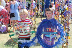 Two boys smiling holding big dream catchers in field