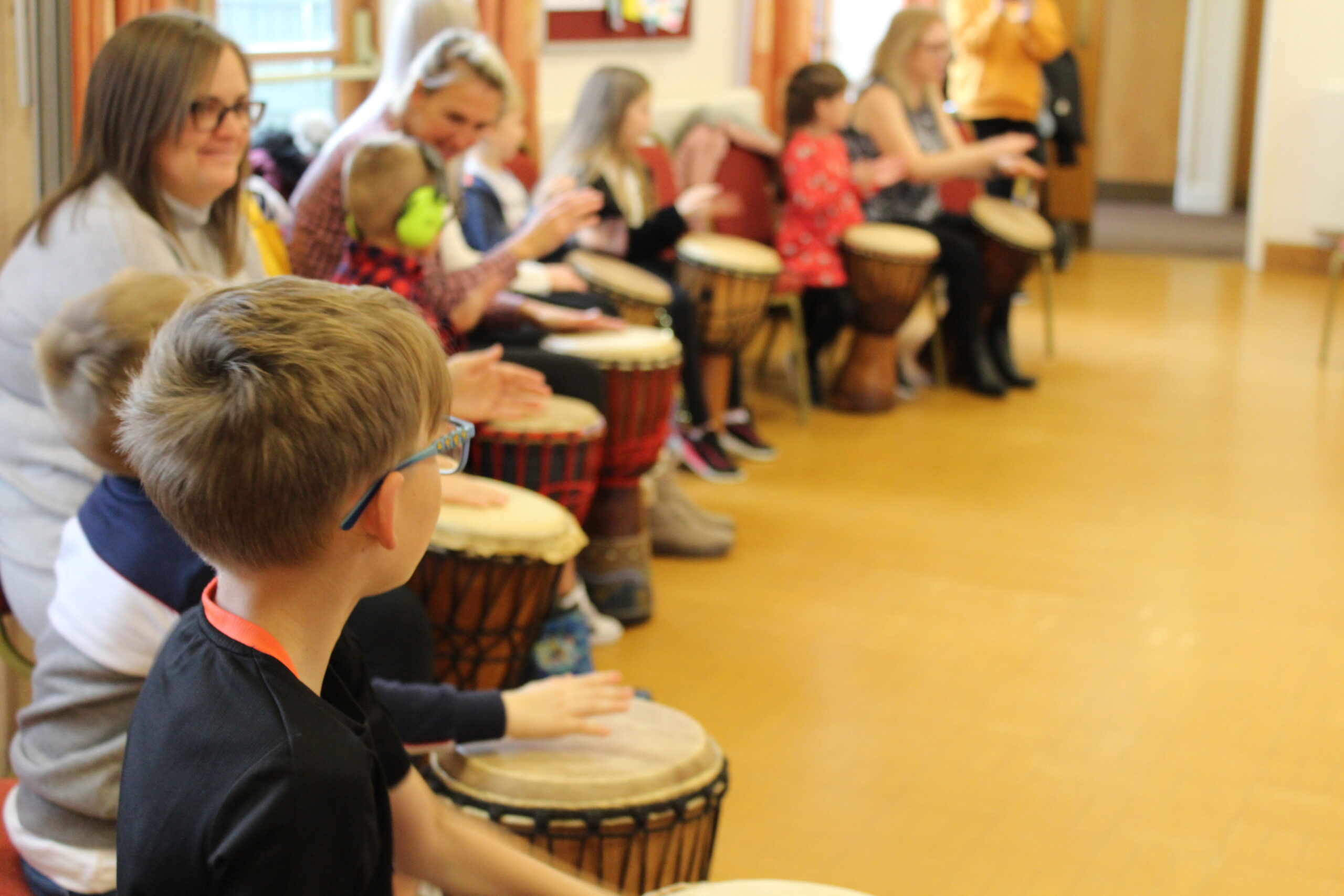 Group of children sitting playing big drums in a room