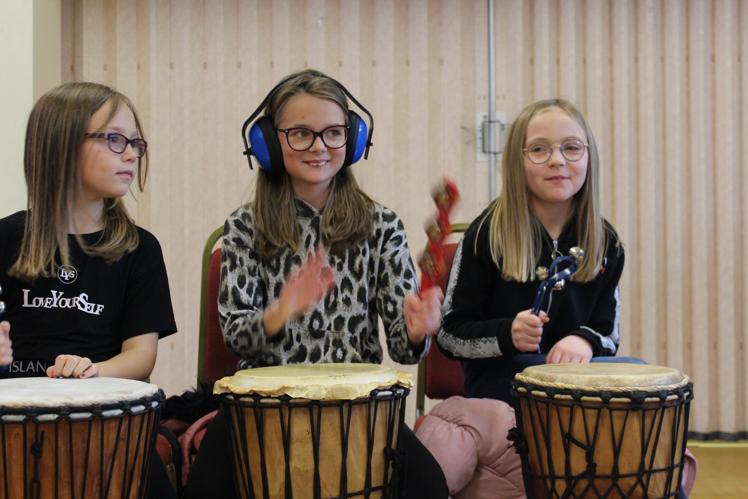 Three girls sitting and drumming