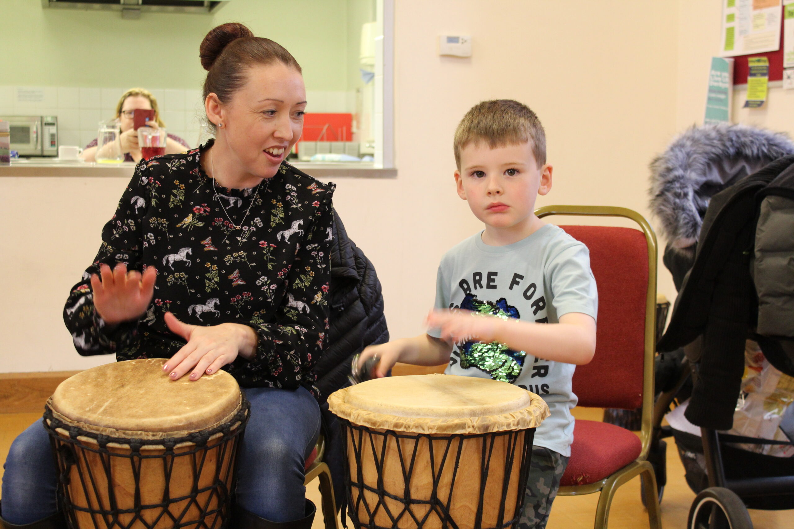 Woman and young boy sitting, drumming in room